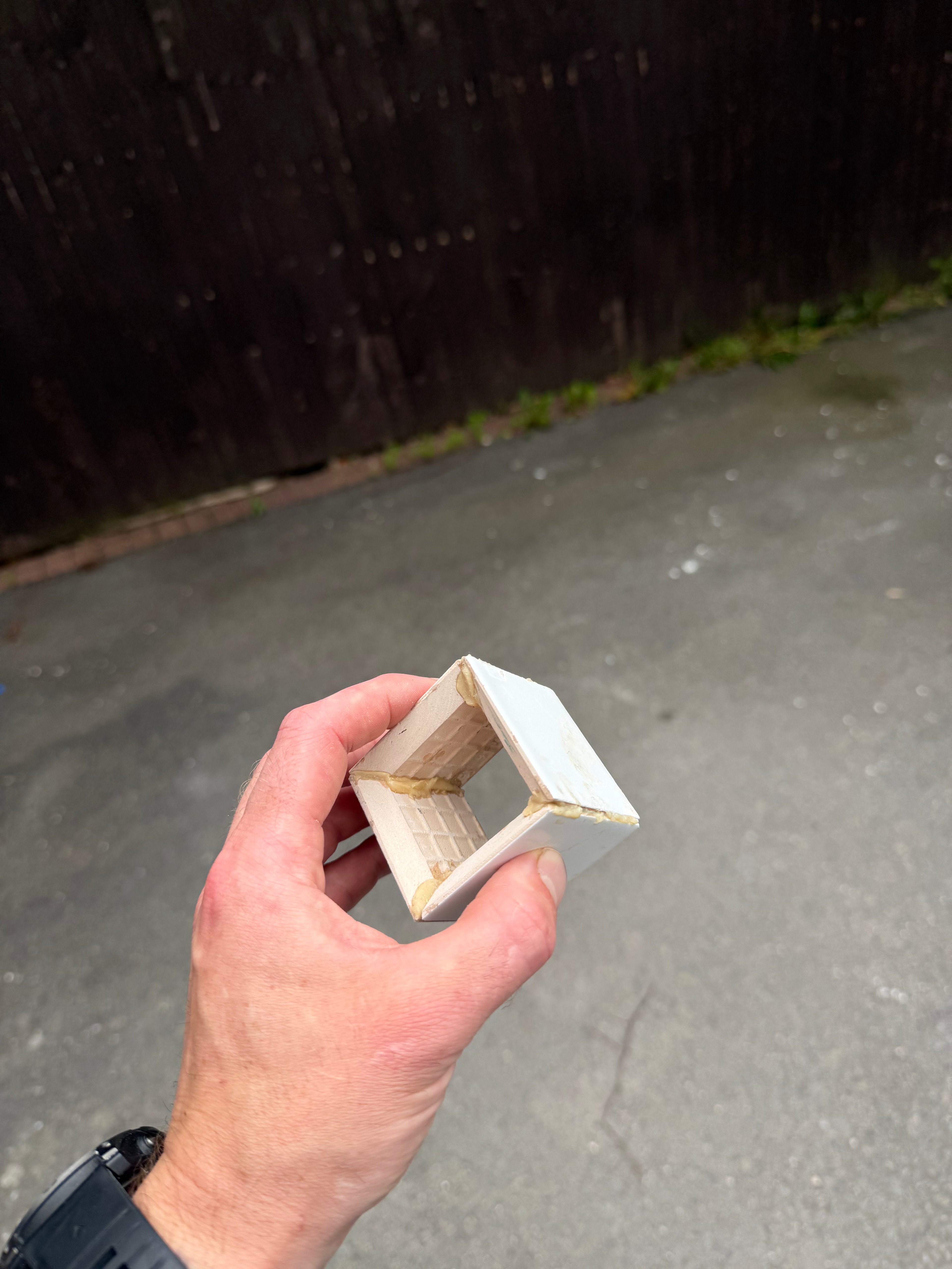 Hand holding a small wooden block with a dark background